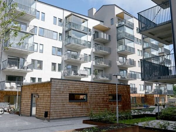 Nybyggda lägenheter med balkonger och detaljer i trä, fotat i dagsljus.