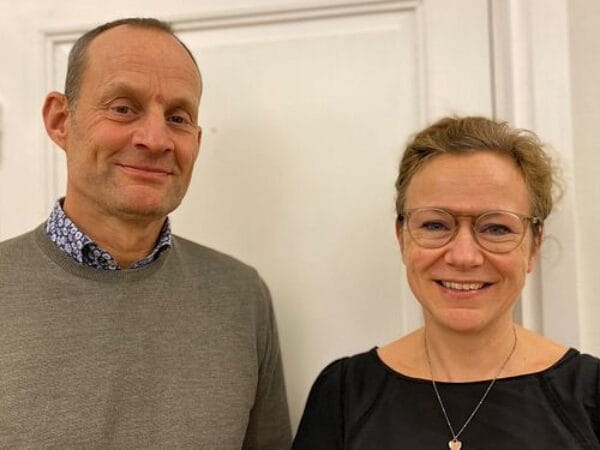En man och kvinna poserar tillsammans framför vit vägg.