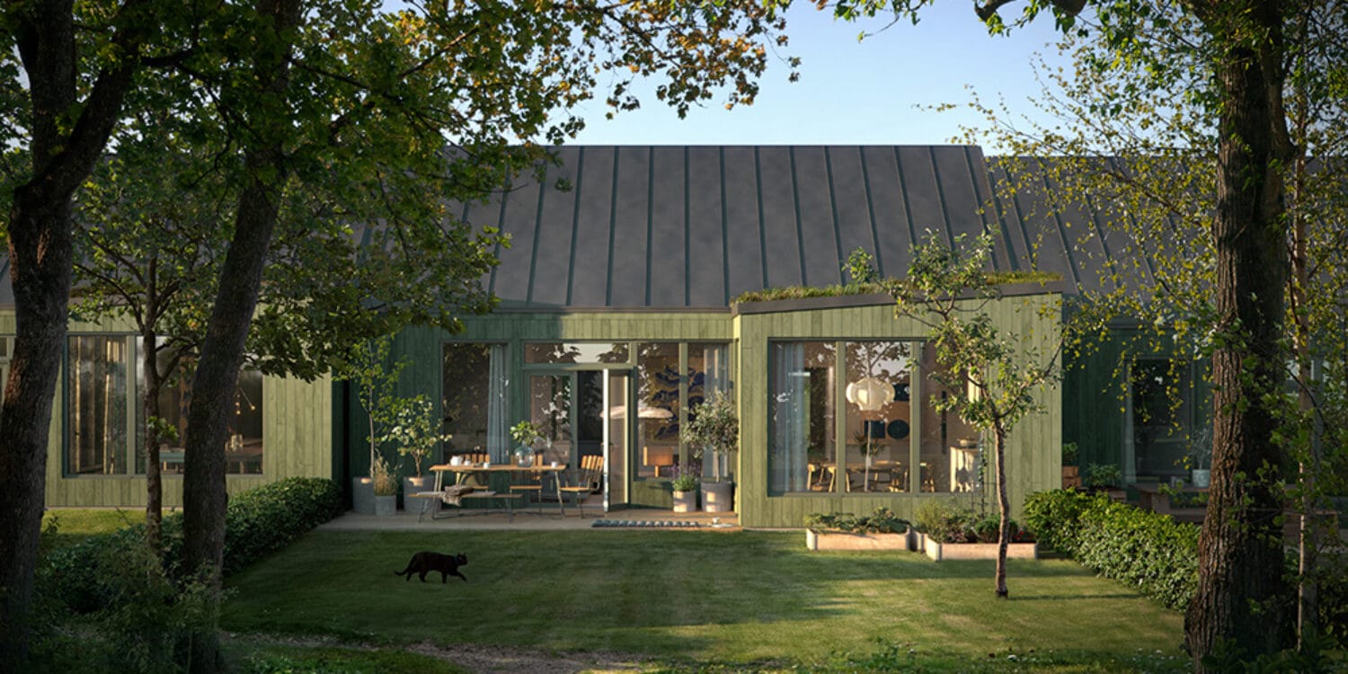 Ett lummigt grönområde breder ut sig bakom ett hus från GBJ bostad i Karlskrona, där stora fönsterpartier öppnar upp mot en välplanerad uteplats i kvällssol.