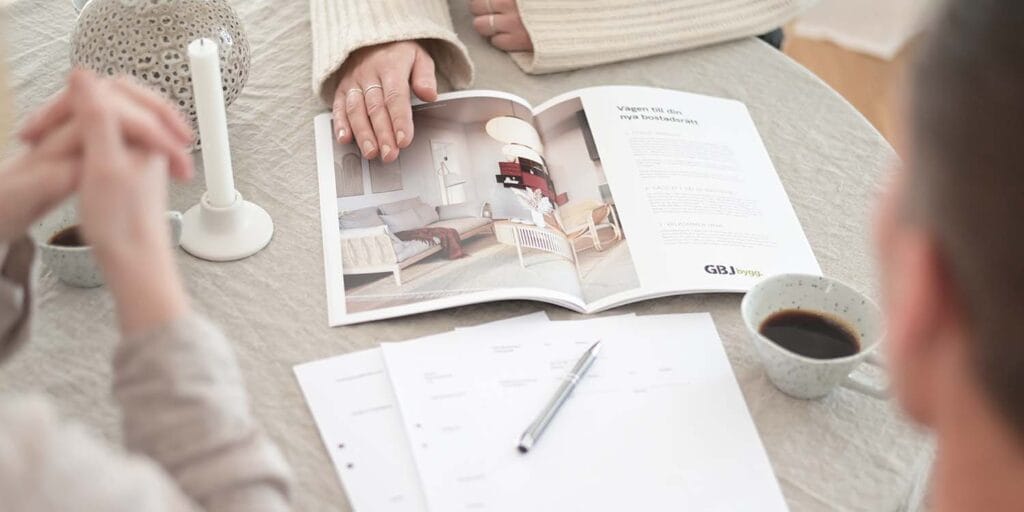 Ett par diskuterar inredningsval över en katalog och anteckningar – ett exempel på det engagemang GBJ bostad väcker i skapandet av personliga hem.