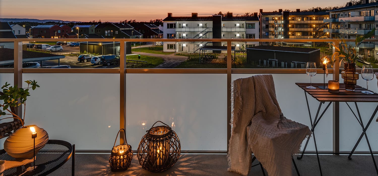 Balkongvy över Hemmeslövs bostadsområde i Båstad med tända lampor, kvällsljus och moderna flerfamiljshus i bakgrunden.