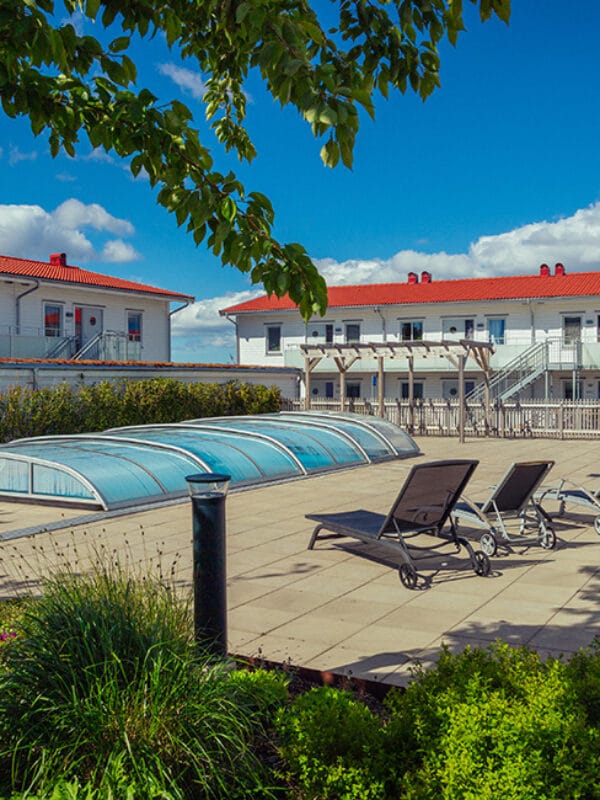 Sittplatser och planteringar omger ett poolområde i ett bostadsprojekt av GBJ bostad, med fokus på sociala ytor och sommarkvalitet.