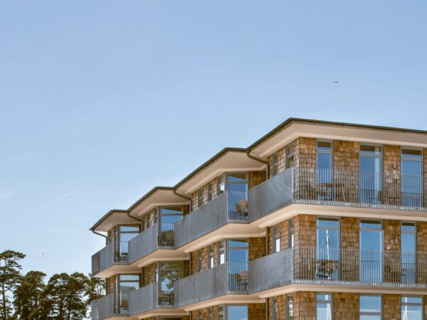 Närbild på byggnadens fasad i GBJ bostads strandnära projekt i Åhus, där arkitekturen kombinerar naturliga material med modern estetik.